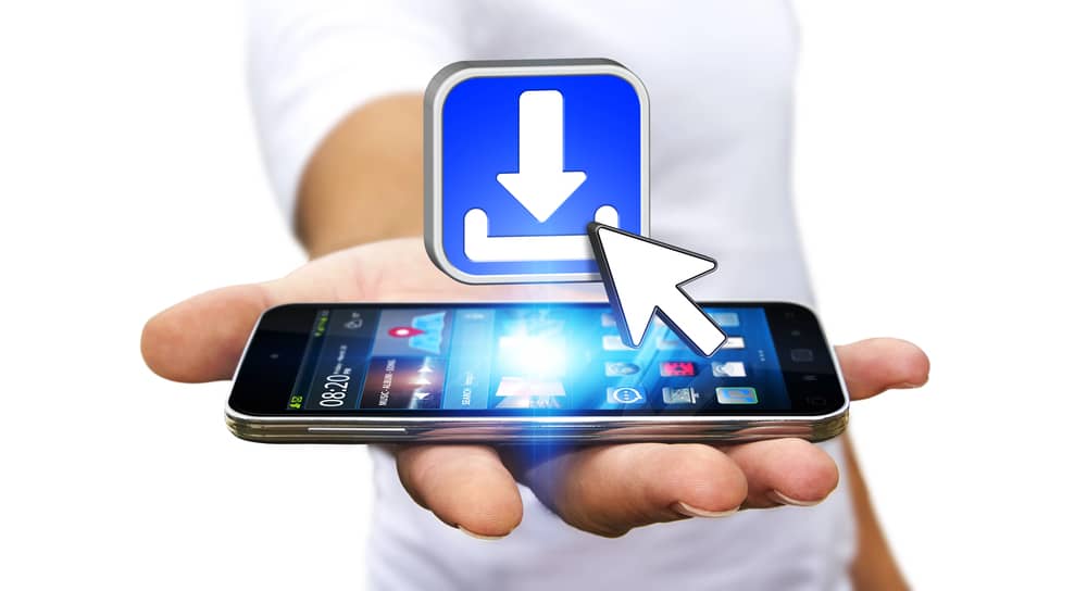 La Evolución del Marketing de Aplicaciones Android: De los Ads a las Ofertas de Afiliados 20 Una mano sostiene un teléfono móvil con un icono de descarga sobre él, representando descargas de aplicaciones o software.