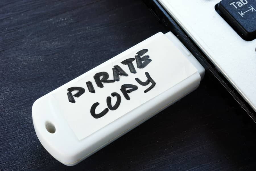 Un pendrive USB con la etiqueta "Copia Pirata" escrita a mano, conectado al puerto de un ordenador portátil.