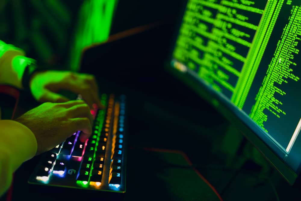 Un hacker ético escribiendo código en un teclado iluminado, analizando un sistema para encontrar vulnerabilidades de seguridad.