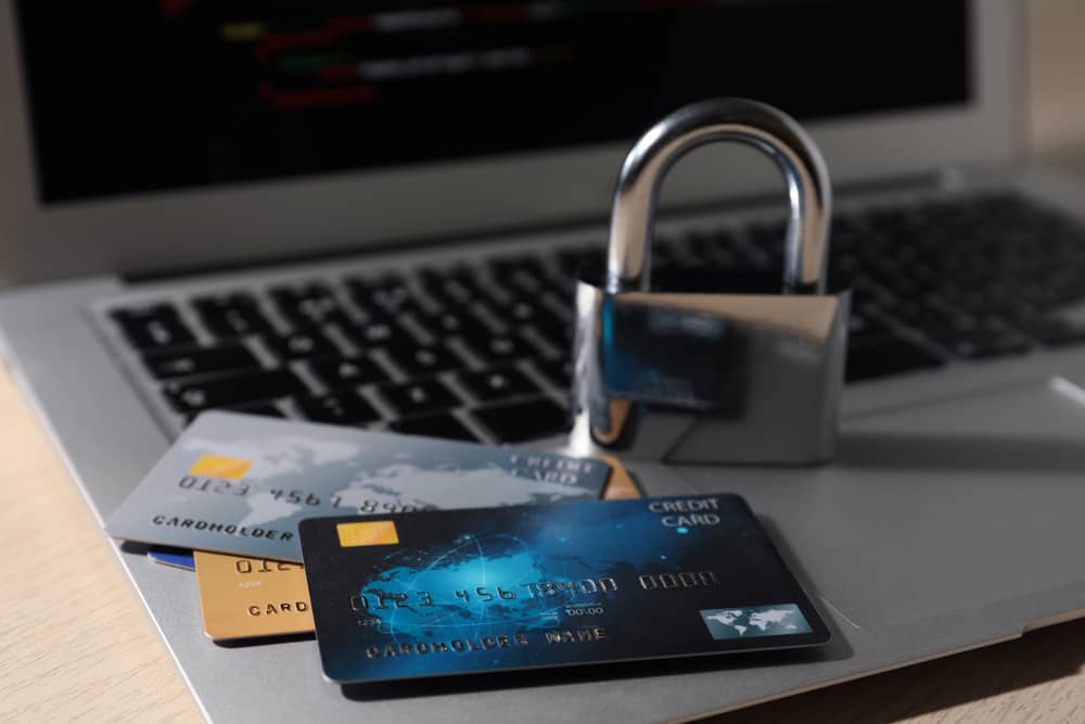 Un candado sobre un portátil con tarjetas de crédito, simbolizando los trucos y la importancia de la seguridad en las transacciones.
